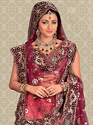 Make your collection more attractive and charming with this impressive dress. This pink net a-line lehenga is nicely embroidered and velvet patch work is done with stone, beads and cutbeads work. The beautiful embroidery on lehenga made it awesome and gives you stylish and attractive look to others. Matching choli and burgundy net dupatta is availble with this lehenga. Slight Color variations are possible due to differing screen and photograph resolutions.