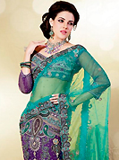 Try out this year top trend, glowing, bold and natural collection. This turquoise and purple net lehenga style saree is nicely designed with embroidered patch work is done with zari, stone, cutbeads and lace work. Saree gives you a singular and dissimilar look. Matching purple blouse is available. Slight color variations are possible due to differing screen and photograph resolution.