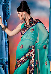 The glamorous silhouette to meet your most dire fashion needs. This turquoise green saree is nicely designed with embroidered border and patch work. Embroidery is done with resham, sequins and zari work in form of floral motifs. This saree gives you a modern and different look in fabulous style. This beautiful drape is crafted with faux georgette fabric. Matching blouse is available with this saree. Slight color variations are possible due to differing screen and photograph resolution.