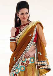 Embroidered sarees are the best choice for a girl to enhance her feminine look. This brown and yellow faux georgette, net and brocade lehenga style saree is nicely designed with embroidered patch work is done with resham, zari, stone and lace work. Beautiful embroidery work on saree make attractive to impress all. This saree gives you a modern and different look in fabulous style. Contrasting maroon blouse is available. Slight color variations are possible due to differing screen and photograph resolution.