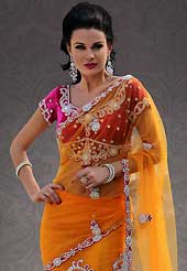 Let your personality articulate for you with this amazing embroidered saree. This orange and magenta net lehenga style saree is nicely designed with embroidery and velvet patch work is done with resham, stone and cutbeads work. Beautiful embroidery work on saree make attractive to impress all. This saree gives you a modern and different look in fabulous style. Contrasting magenta blouse is available. Slight color variations are possible due to differing screen and photograph resolution.