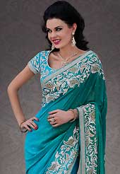 Dreamy variation on shape and forms compliment your style with tradition. This turquoise and blue georgette saree is nicely designed with embroidery patch work is done with stone and cutbeads work. Beautiful embroidery work on saree make attractive to impress all. This saree gives you a modern and different look in fabulous style. Matching blouse is available. Slight color variations are possible due to differing screen and photograph resolution.