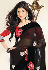 The glamorous silhouette to meet your most dire fashion needs. This black net and chiffon saree is nicely designed with embroidery patch work is done with resham, zari, stone and beads work. Beautiful embroidery work on saree make attractive to impress all. This saree gives you a modern and different look in fabulous style. Contrasting red blouse is available. Slight color variations are possible due to differing screen and photograph resolution.