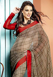 Make a trendy look with this classic printed saree. This beautiful dusty brown and grey faux georgette saree is nicely designed with geometric print and graceful patch border. Beautiful print work on saree make attractive to impress all. It will enhance your personality and gives you a singular look. Contrasting red blouse is available with this saree. Slight color variations are due to differing screen and photography resolution.