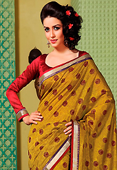 An occasion wear perfect is ready to rock you. This mustard art silk saree is nicely designed with floral print, self weaving zari, lace and patch bordered work. Beautiful embroidery work on saree make attractive to impress all. This saree gives you a modern and different look in fabulous style. Contrasting red blouse is available. Slight color variations are possible due to differing screen and photograph resolution.